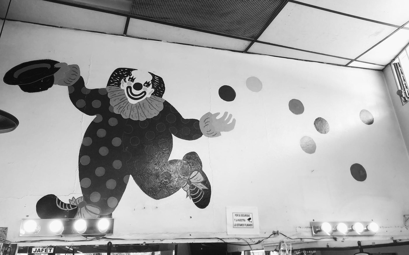 El payaso pintado en la pared de la barbería, con su bombín en la mano